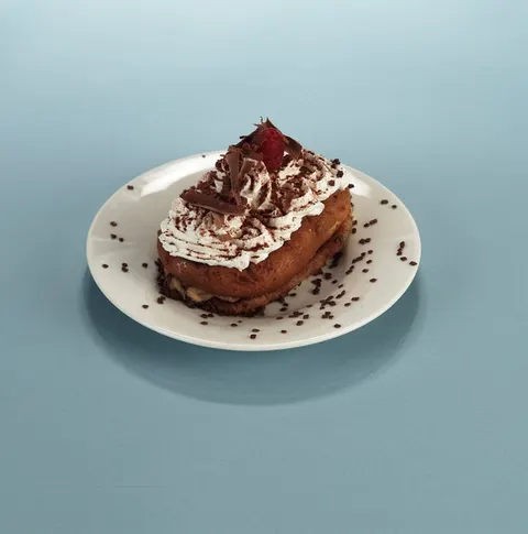 A cream-topped pastry shell with a strawberry quarter
