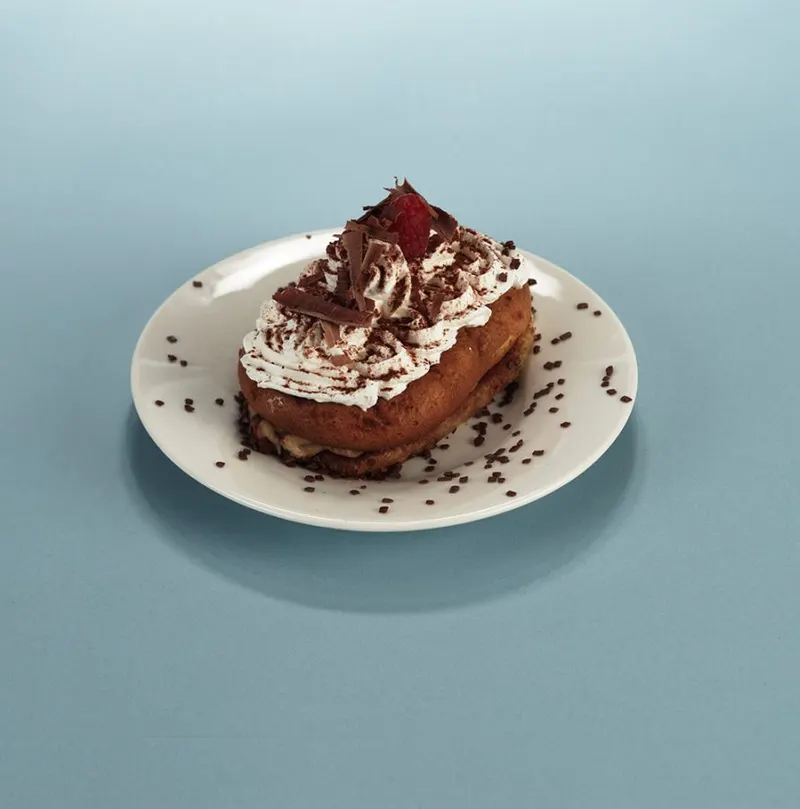 Cream-topped pastry shell with chocolate shavings and a strawberry quarter